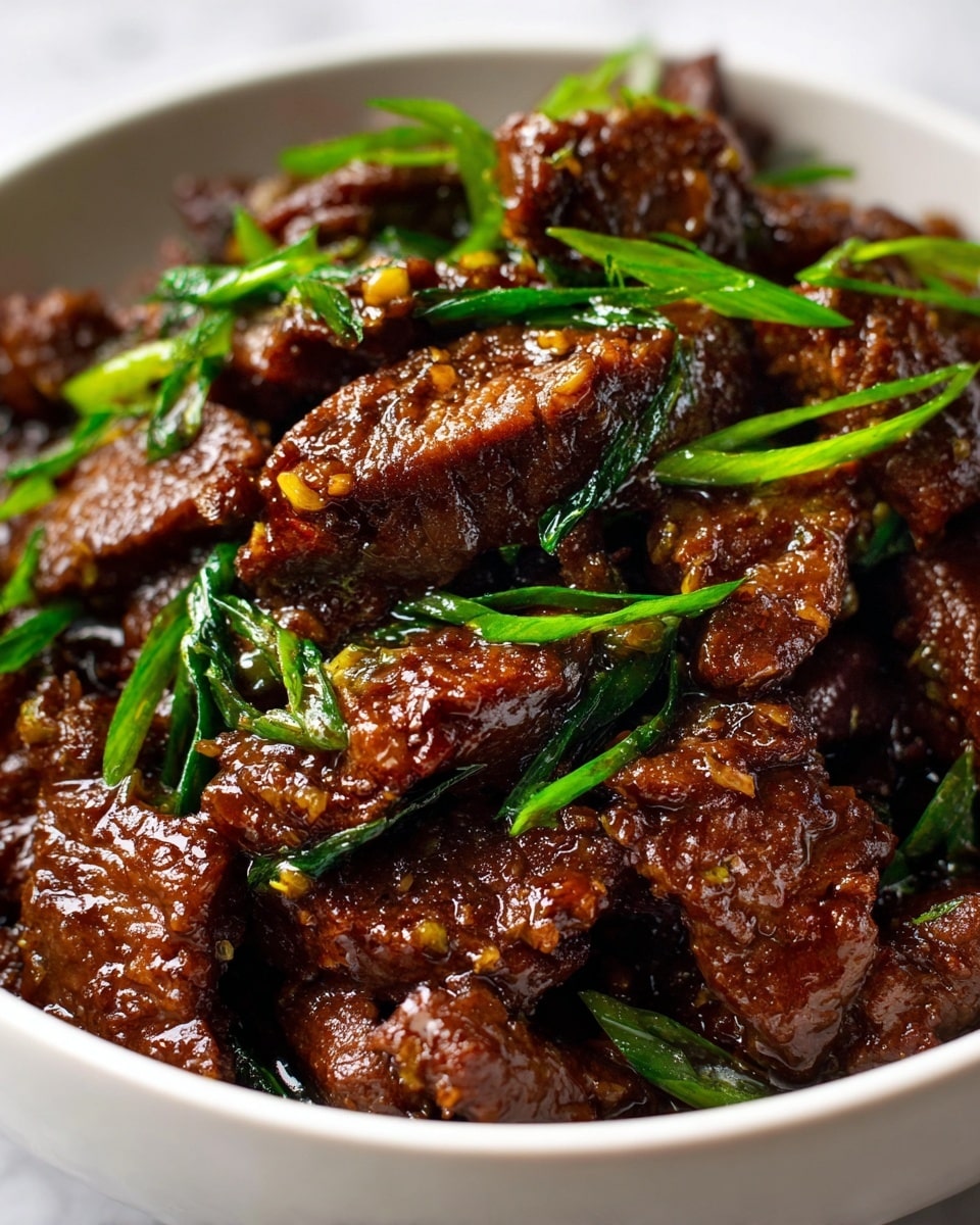 A close-up view of dark brown cooked beef pieces mixed with bright green chopped spring onions, all coated in a shiny, thick sauce that gives the meat a glossy look. The beef pieces are layered unevenly, showing different textures with some tender and others slightly crisp around the edges. The spring onions are scattered on top and in between the beef, adding a fresh pop of green to the rich, brown meat. The dish sits in a white bowl on a white marbled surface, highlighting the vibrant colors and tasty textures of the food. photo taken with an iphone --ar 4:5 --v 7