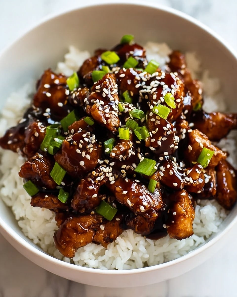 Large white bowl filled with a generous serving of glossy, richly glazed teriyaki chicken pieces nestled on a fluffy bed of steamed white rice, generously sprinkled with toasted sesame seeds and chopped fresh green onions, whole dish presented with vibrant colors and a shiny finish, photographed from a 3/4 angle on a white marble countertop, natural lighting highlighting the savory textures, professional food magazine hero shot photo taken with an iphone --ar 4:5 --v 7